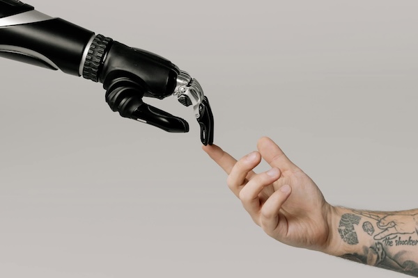 bras tatoué et bras robotique se touchent